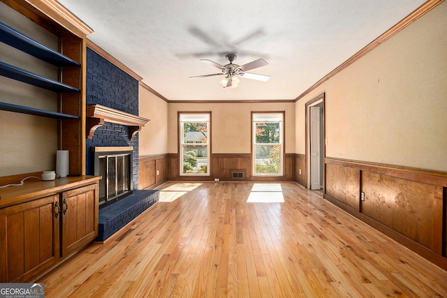 unfurnished living room featuring crown molding, a textured ceiling, light wood-type flooring, and a brick fireplace