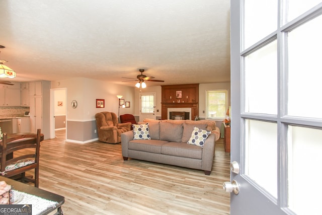 living room featuring light hardwood / wood-style floors, a textured ceiling, and ceiling fan