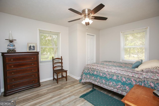 bedroom with a ceiling fan, baseboards, light wood-style floors, a closet, and a textured ceiling