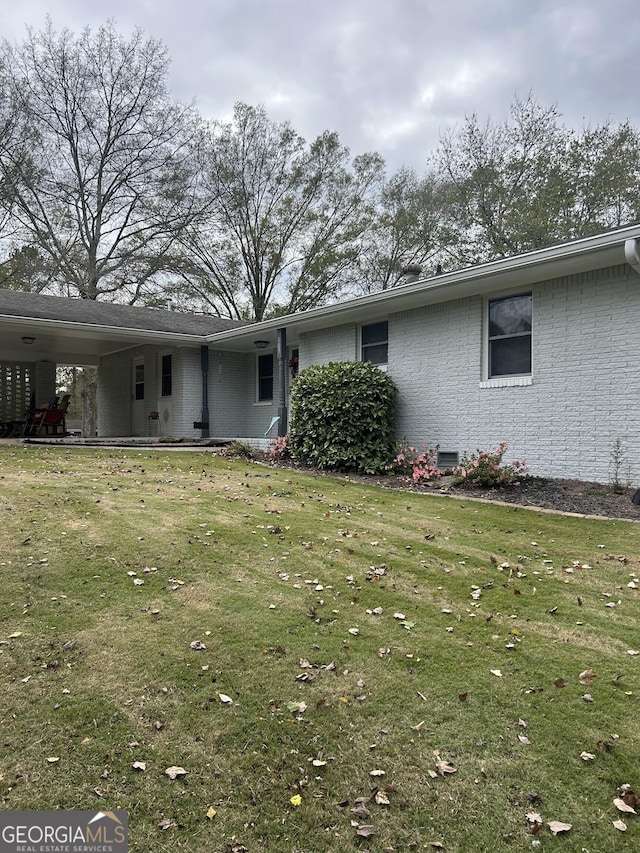 view of front facade with crawl space, an attached carport, brick siding, and a front lawn