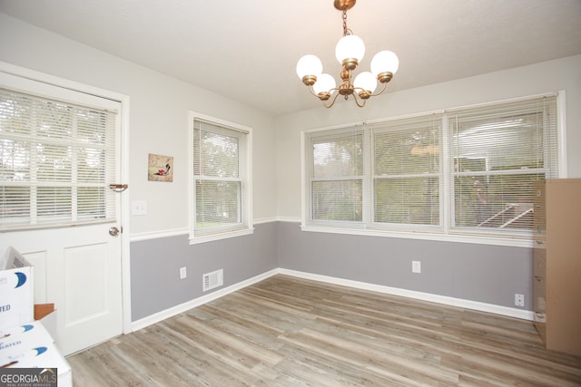 unfurnished dining area featuring hardwood / wood-style floors and a notable chandelier