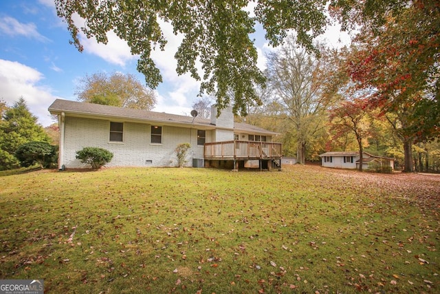 back of property with a yard, a wooden deck, an outdoor structure, crawl space, and brick siding