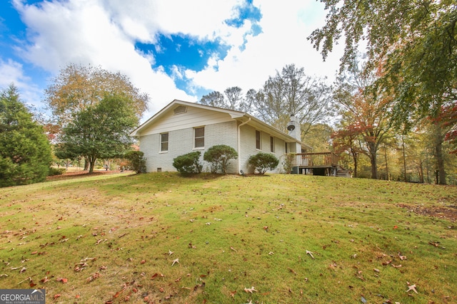 view of side of home with a wooden deck and a lawn