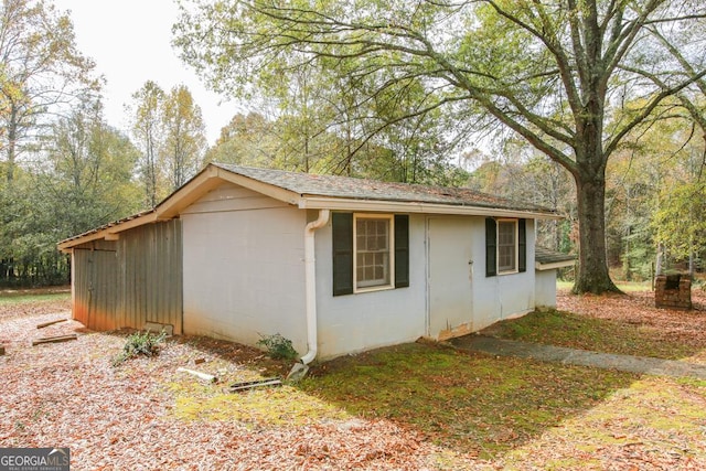 view of side of home with roof with shingles and concrete block siding