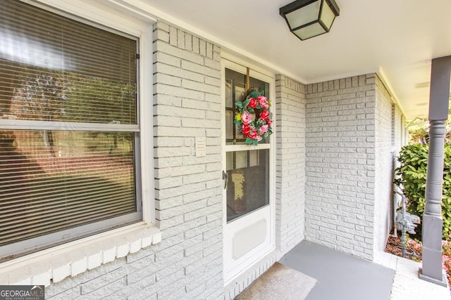 doorway to property with brick siding and a porch