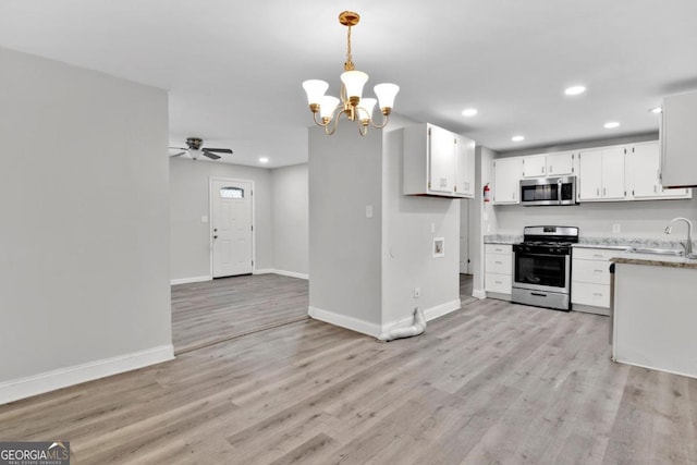 kitchen with light hardwood / wood-style flooring, white cabinetry, hanging light fixtures, and appliances with stainless steel finishes