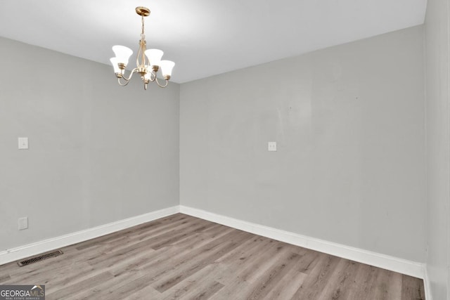 unfurnished room featuring a chandelier and light wood-type flooring