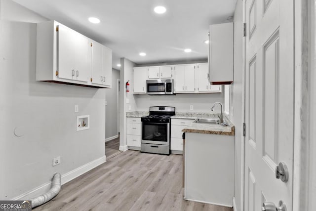 kitchen featuring white cabinets, stainless steel appliances, light hardwood / wood-style flooring, and sink