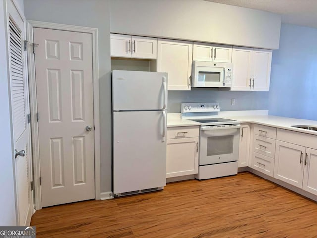 kitchen featuring white appliances, light hardwood / wood-style floors, and white cabinets