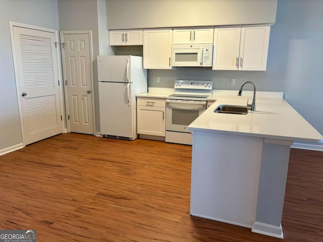 kitchen with light hardwood / wood-style flooring, kitchen peninsula, sink, white cabinets, and white appliances