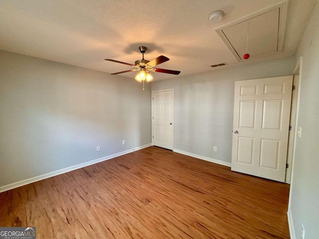 unfurnished bedroom featuring ceiling fan, wood-type flooring, and a textured ceiling