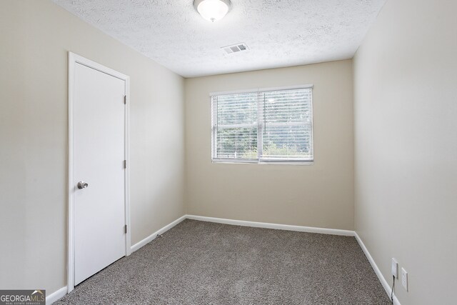 carpeted empty room featuring a textured ceiling