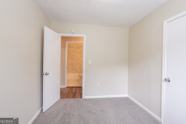 unfurnished bedroom with a textured ceiling and carpet flooring