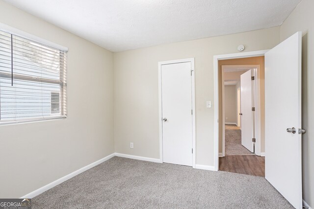 unfurnished bedroom featuring a textured ceiling and carpet floors