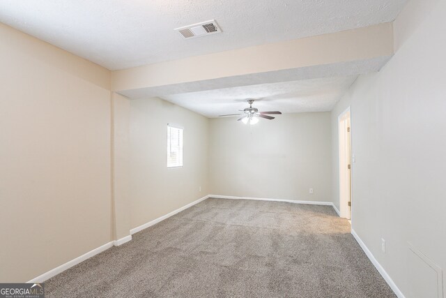 carpeted spare room featuring ceiling fan and a textured ceiling