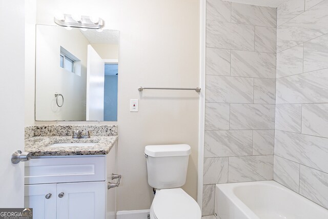 full bathroom with tiled shower / bath, vanity, and toilet