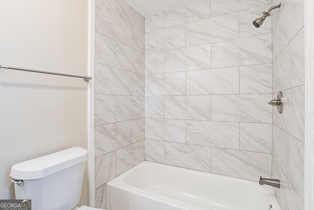 bathroom featuring toilet and tiled shower / bath