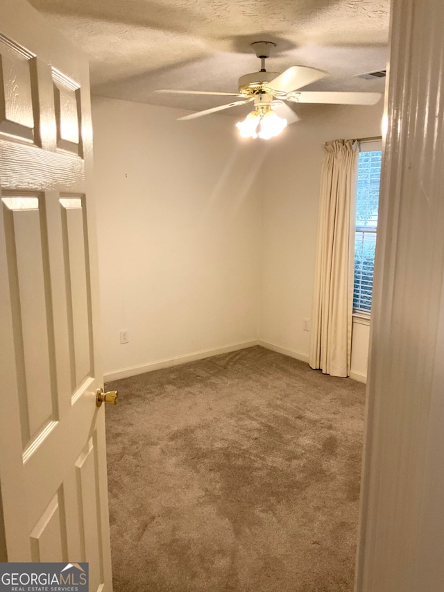 spare room featuring a textured ceiling, carpet floors, and ceiling fan