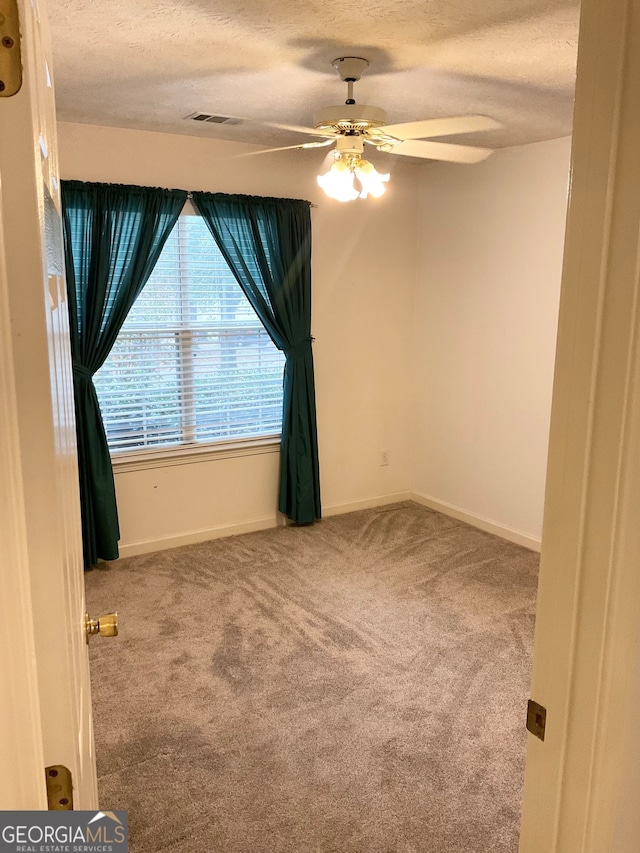 empty room featuring ceiling fan, carpet flooring, and a textured ceiling