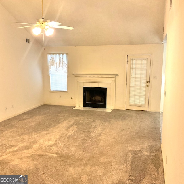 unfurnished living room featuring ceiling fan, carpet, vaulted ceiling, and a tile fireplace