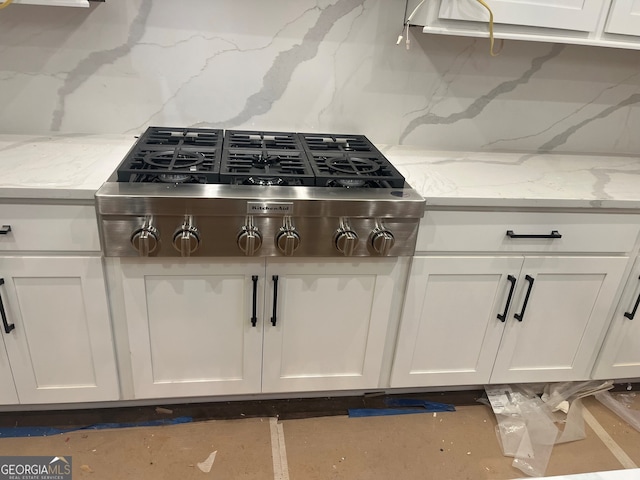 kitchen featuring tasteful backsplash, light stone countertops, stainless steel gas cooktop, and white cabinets