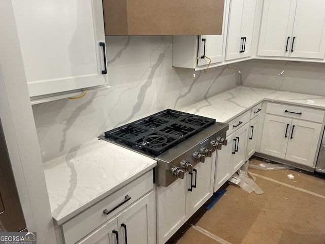 kitchen featuring stainless steel gas stovetop, tasteful backsplash, light stone countertops, and white cabinets