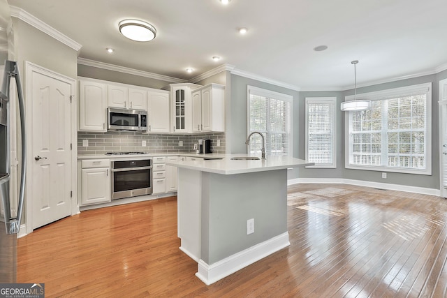 kitchen featuring white cabinets, light wood-type flooring, appliances with stainless steel finishes, and sink