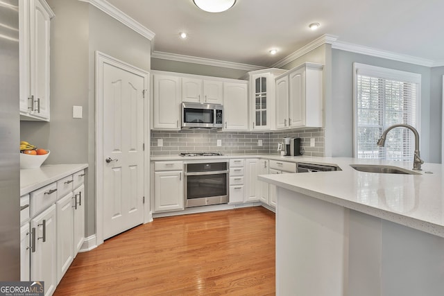 kitchen with white cabinetry, sink, appliances with stainless steel finishes, light hardwood / wood-style flooring, and crown molding