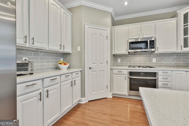 kitchen with stainless steel appliances, white cabinetry, light wood-type flooring, and tasteful backsplash