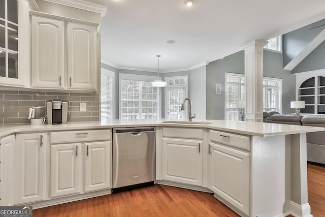 kitchen with sink, white cabinets, ornate columns, light wood-type flooring, and dishwasher