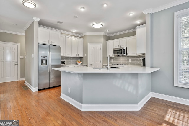 kitchen featuring white cabinets, light hardwood / wood-style floors, kitchen peninsula, and appliances with stainless steel finishes