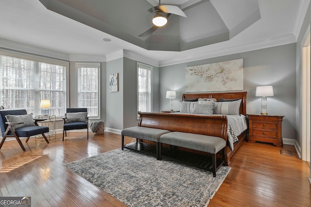 bedroom with ornamental molding, wood-type flooring, ceiling fan, and a raised ceiling