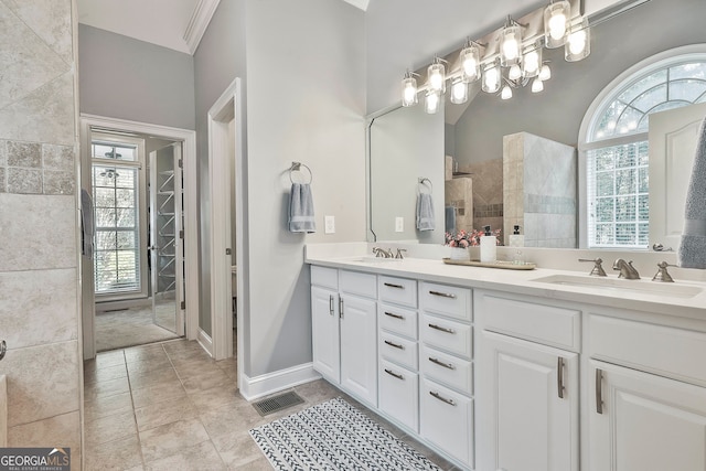 bathroom featuring a wealth of natural light, vanity, tile patterned flooring, and tiled shower