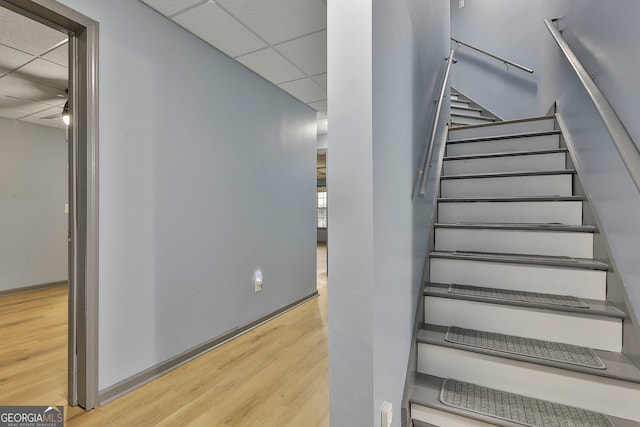 stairway featuring a paneled ceiling and hardwood / wood-style floors