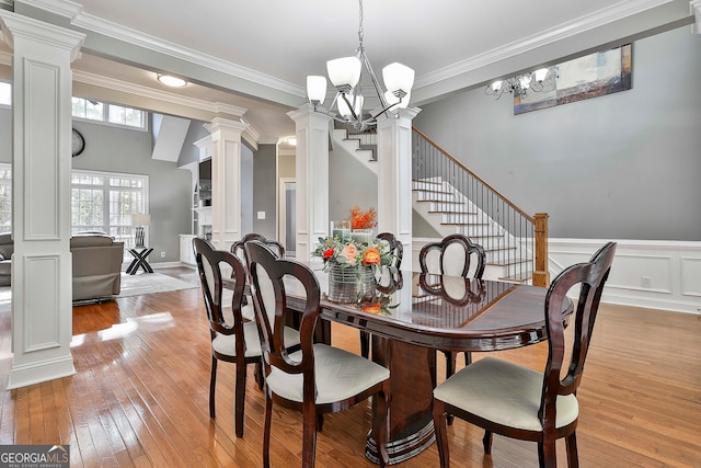 dining space with ornamental molding, ornate columns, light hardwood / wood-style flooring, and a notable chandelier