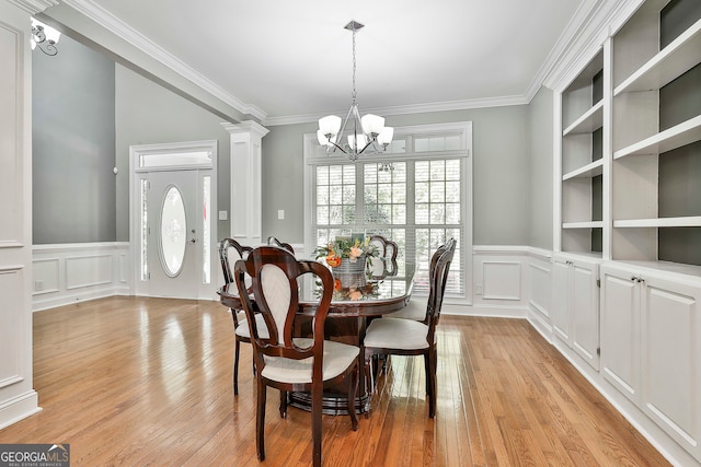 dining space with ornamental molding, light hardwood / wood-style flooring, ornate columns, and an inviting chandelier