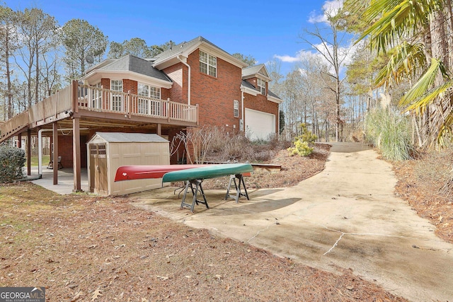 back of house featuring a garage, a wooden deck, and a storage unit