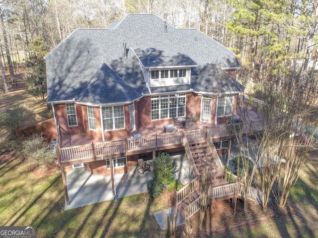 rear view of property featuring a wooden deck and a patio area