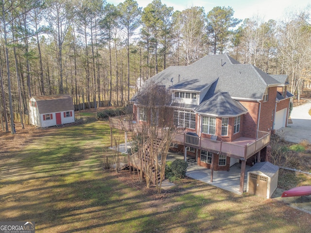 back of property featuring a storage shed, a wooden deck, and a yard