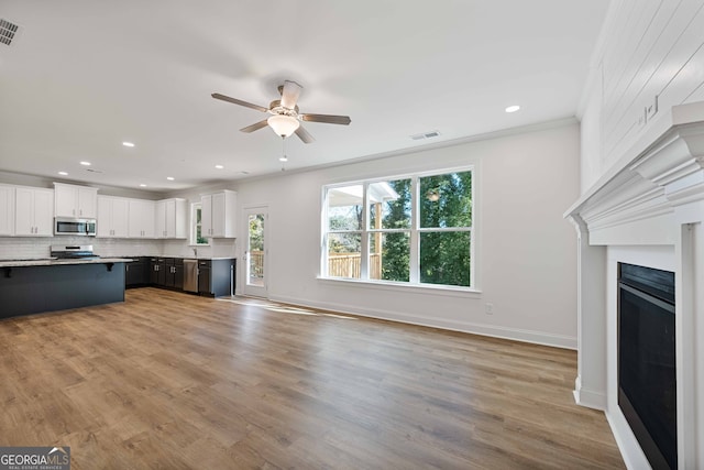 unfurnished living room with ceiling fan, ornamental molding, and light wood-type flooring