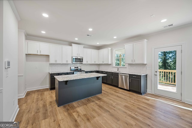 kitchen featuring white cabinets, stainless steel appliances, a kitchen island, and plenty of natural light