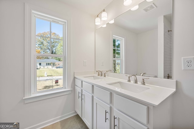 bathroom with tile patterned floors, a wealth of natural light, vanity, and toilet