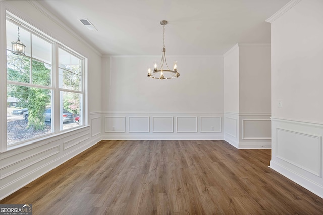 empty room with an inviting chandelier, crown molding, and dark wood-type flooring