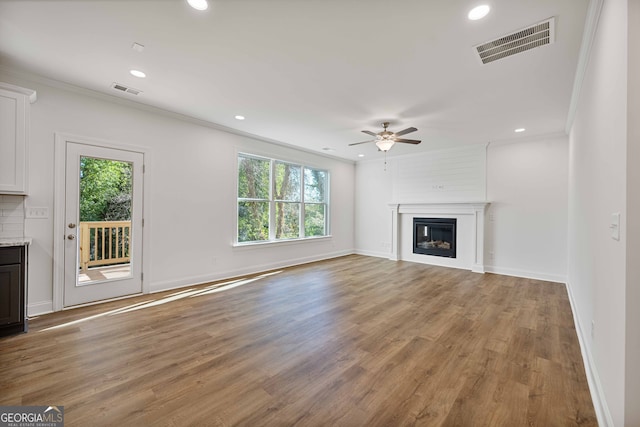 unfurnished living room with crown molding, a fireplace, ceiling fan, and light hardwood / wood-style floors