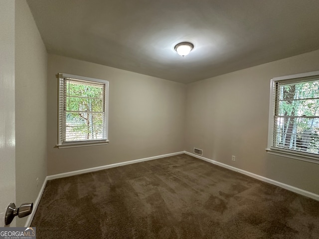 unfurnished room with dark carpet and plenty of natural light