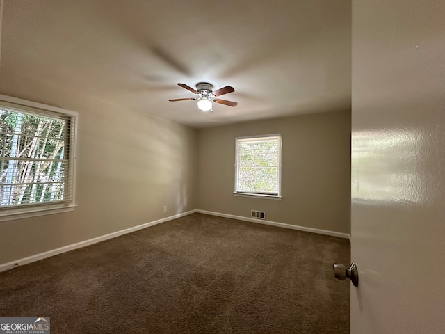 spare room featuring dark carpet and ceiling fan