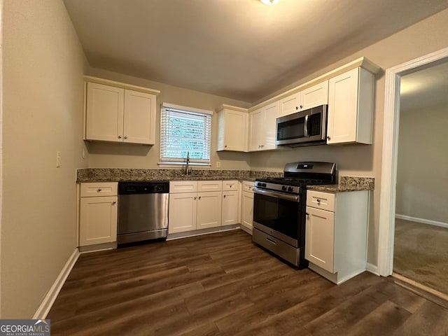 kitchen with white cabinets, dark stone counters, dark hardwood / wood-style floors, sink, and stainless steel appliances