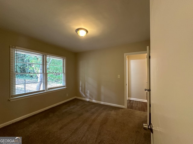 spare room featuring dark carpet