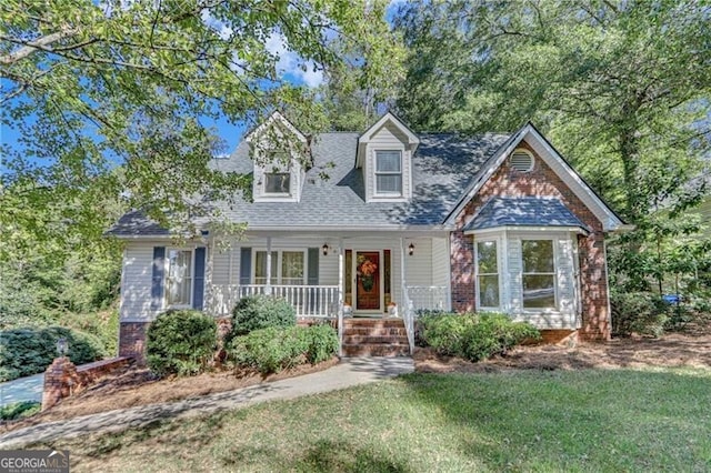 cape cod-style house featuring covered porch, a front lawn, brick siding, and a shingled roof