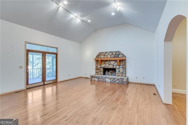 unfurnished living room featuring vaulted ceiling, a fireplace, light wood-type flooring, and rail lighting